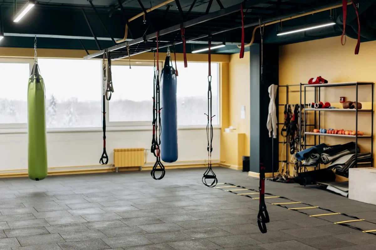 A gym training space with suspension straps, punching bags and weights.