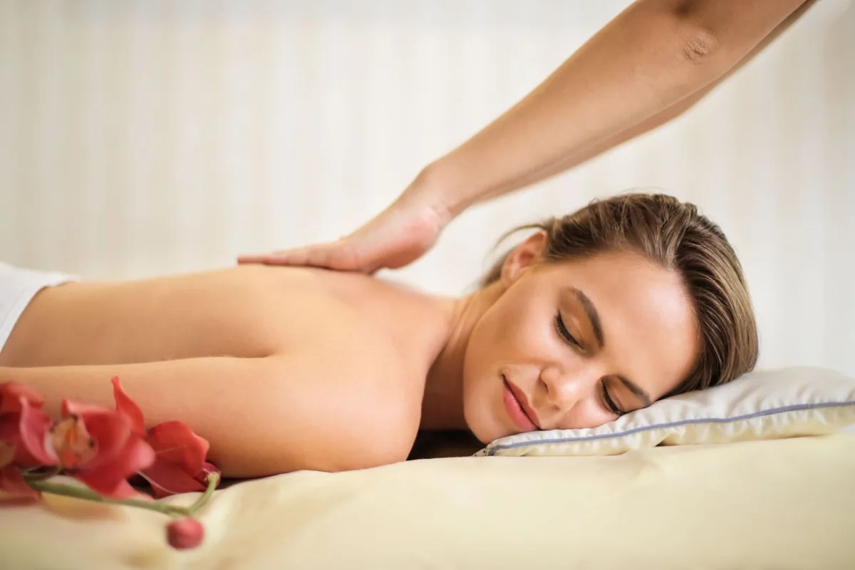 A woman receiving a shoulder massage on a treatment bed.
