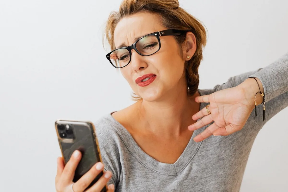 A woman looking at her smartphone while sitting on a sofa.