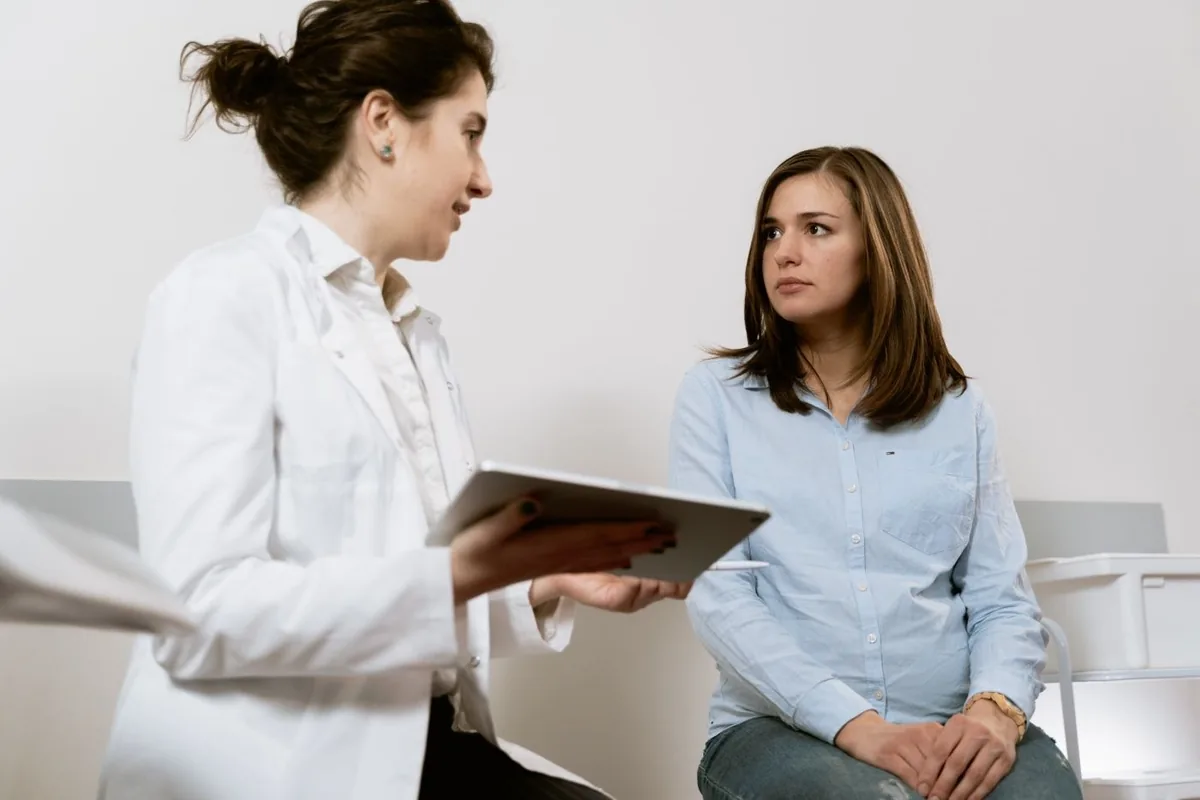 A practitioner discussing information on a tablet with a patient.
