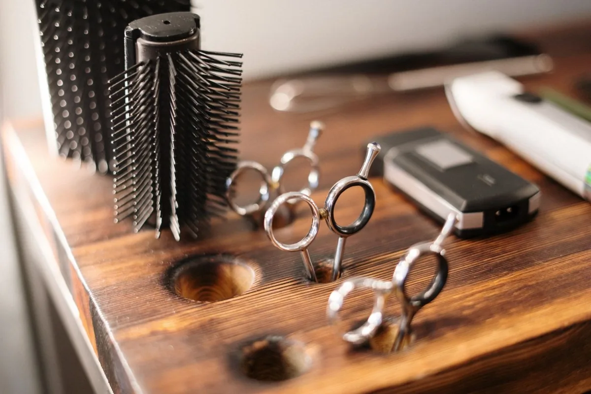 Hairbrushes, scissors and clippers arranged on a salon worktop.
